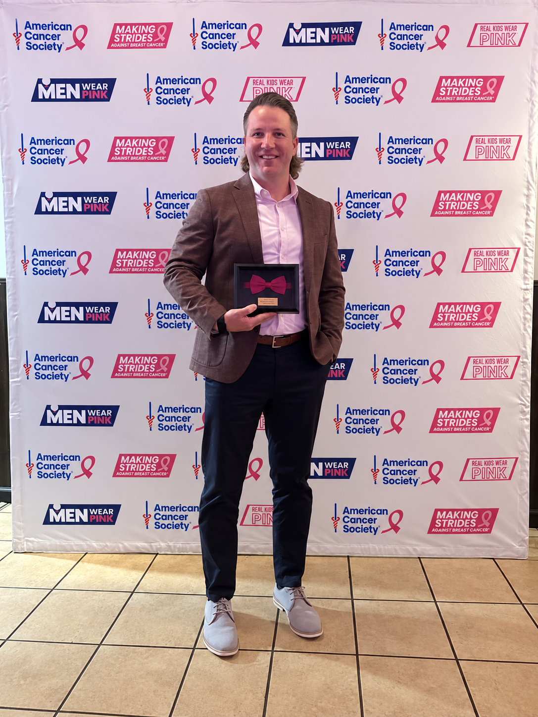 Jeff holding an award at a Men Wear Pink event